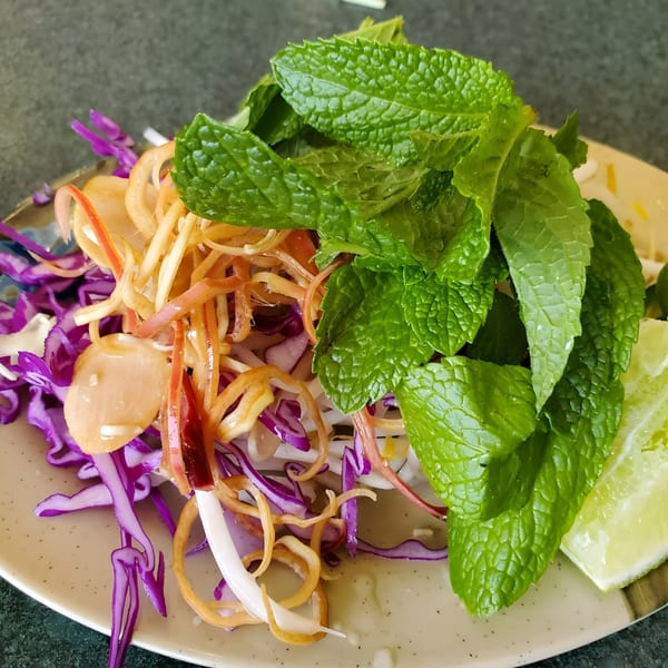 A vibrant Vietnamese salad with shredded purple cabbage, pickled onions, and fresh mint leaves.